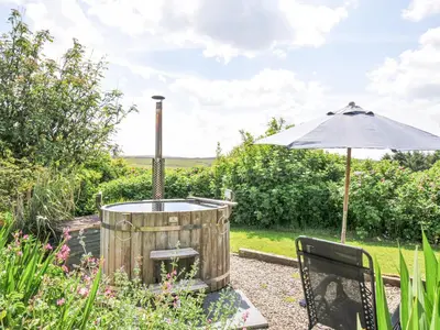 a hot tub and an umbrella in a garden at Smugglers in Bodmin