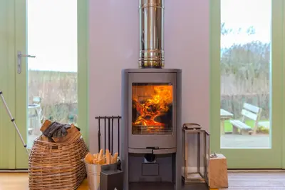 a wood stove with a fire in a room at Smugglers in Bodmin
