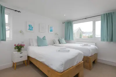 two beds in a room with two windows at Captain's Walk in Newquay