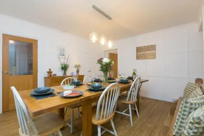 a dining room with a wooden table and chairs at Captain's Walk in Newquay