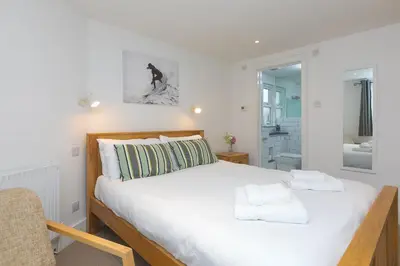 a bedroom with a large white bed and a bathroom at Captain's Walk in Newquay