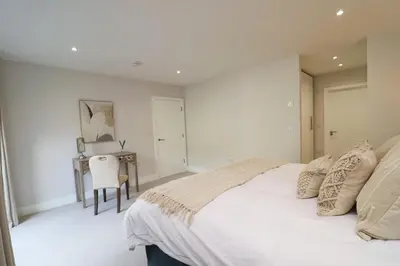 a white bedroom with a bed and a desk at Fifty Steps from the beach! in St Merryn