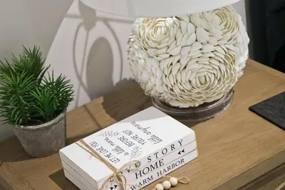 a table with a book and a lamp and a vase at Fifty Steps from the beach! in St Merryn