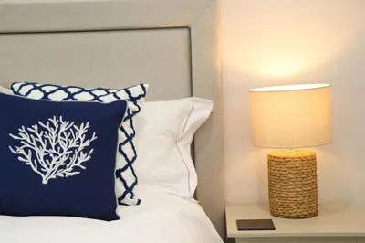 a bed with a blue and white pillow next to a lamp at Fifty Steps from the beach! in St Merryn