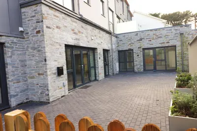 an empty courtyard of a brick building with a wooden fence at Fifty Steps from the beach! in St Merryn