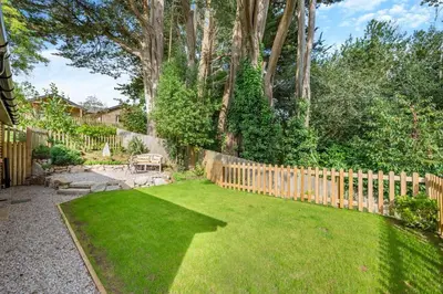 a backyard with a wooden fence and green grass at 1 Bed in Tresillian oc-p30116 in Saint Clement