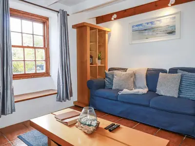 a living room with a blue couch and a table at Rose Cottage in Falmouth