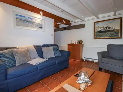 a living room with a blue couch and a chair at Rose Cottage in Falmouth