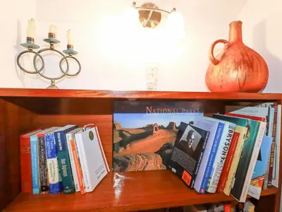 a book shelf with books and a pumpkin and candles at Rose Cottage in Falmouth
