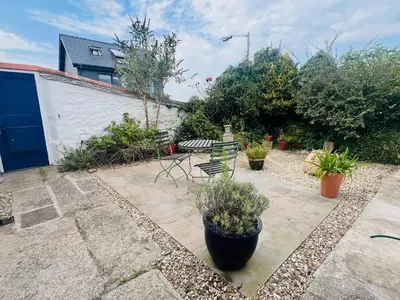 a patio with a chair and plants in a yard at Rose Cottage in Falmouth
