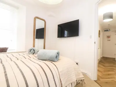 a bedroom with a bed with a tv on the wall at 5 Fistral Waves in Newquay
