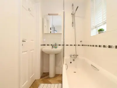 a white bathroom with a tub and a sink at 5 Fistral Waves in Newquay