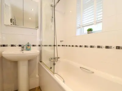 a white bathroom with a sink and a shower at 5 Fistral Waves in Newquay