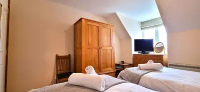 a bedroom with two beds and a wooden cabinet at 15 Penhale, Perranporth in Perranporth