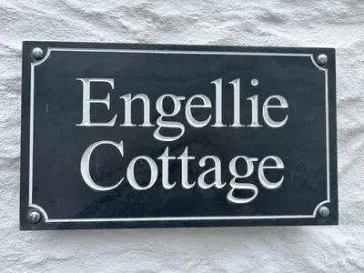a sign that reads inequitable college hanging on a wall at Engellie Cottage in Perranporth