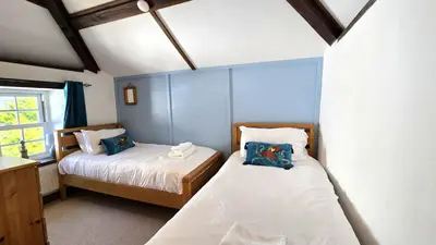 two beds in a room with blue walls at Engellie Cottage in Perranporth