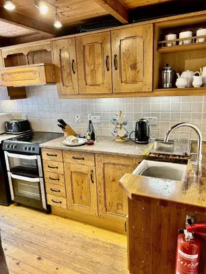 a kitchen with wooden cabinets and a sink at Engellie Cottage in Perranporth
