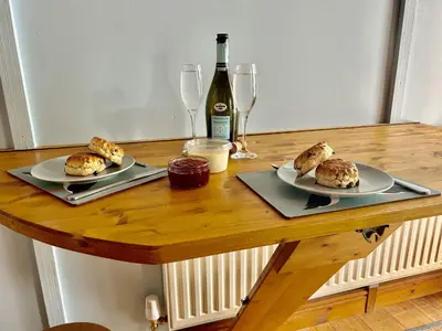 a table with two plates of food and a bottle of wine at Engellie Cottage in Perranporth