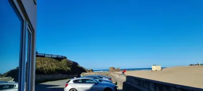 a couple of cars parked next to the beach at Sand Bay, Perranporth in Perranporth