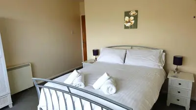 a bedroom with a bed with white sheets and pillows at Sand Bay, Perranporth in Perranporth