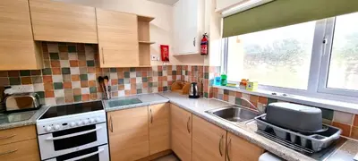 a kitchen with a sink and a stove and a window at Sand Bay, Perranporth in Perranporth
