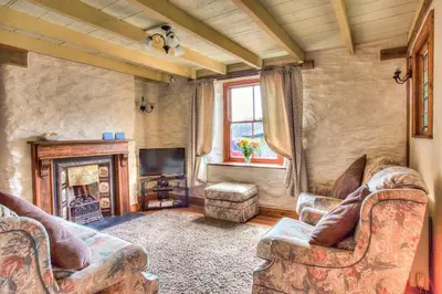 a living room with a couch and a fireplace at Mona's Cottage - Private Parking, Sea Views, Garden & Close To Harbour & Beach in Charlestown