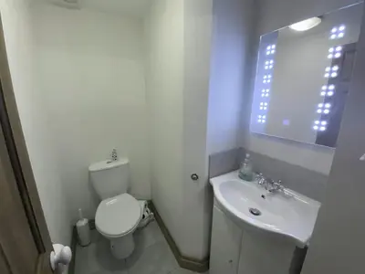 a white bathroom with a toilet and a sink at Mona's Cottage - Private Parking, Sea Views, Garden & Close To Harbour & Beach in Charlestown