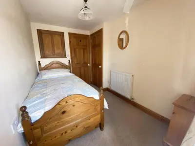 a bedroom with a wooden bed in a room at Mona's Cottage - Private Parking, Sea Views, Garden & Close To Harbour & Beach in Charlestown