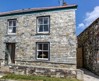 a brick house with two windows on the side at Mona's Cottage - Private Parking, Sea Views, Garden & Close To Harbour & Beach in Charlestown