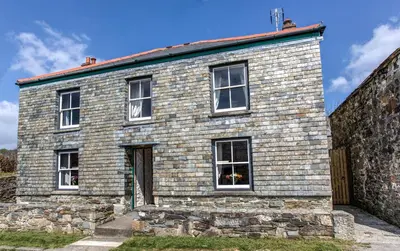 a stone house with white windows and a stone wall at Mona's Cottage - Private Parking, Sea Views, Garden & Close To Harbour & Beach in Charlestown