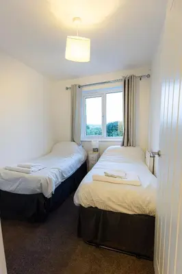 two beds in a room with a window at Piran View in Perranporth