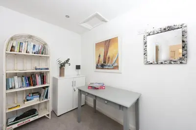 a room with a desk and a book shelf at Samson Cottage in Saint Mawgan