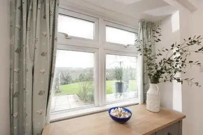 a window with a vase of flowers on a wooden table at Samson Cottage in Saint Mawgan
