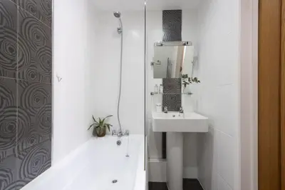 a white bathroom with a sink and a shower at Samson Cottage in Saint Mawgan