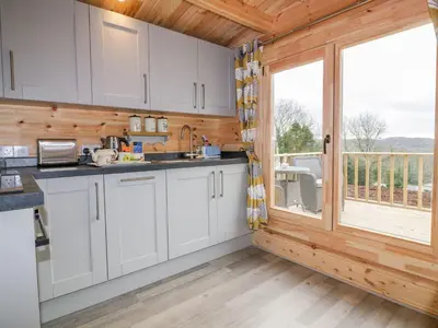 a kitchen with white cabinets and a large window at Little Orchard Lodge in Truro