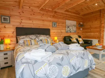 a bedroom with a bed in a log cabin at Little Orchard Lodge in Truro