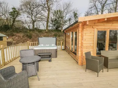 a deck with a barbecue grill on a wooden cabin at Little Orchard Lodge in Truro