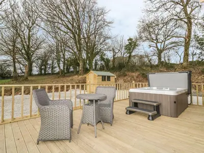 a deck with a ping pong table and chairs at Little Orchard Lodge in Truro