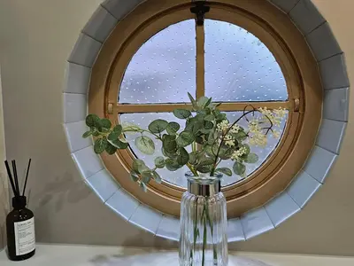 a vase with flowers sitting in front of a window at Mayflower in St Austell