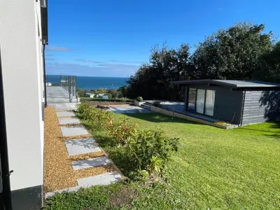 a backyard with a house and a lawn with a pathway at Mayflower in St Austell
