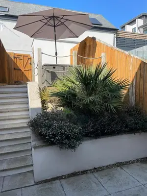 a patio with an umbrella and some plants and stairs at Luxury 3-Bed house, Beach 300m, Sleeps 6, Parking in Newquay