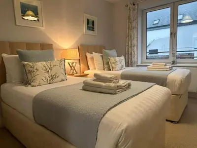 two beds in a room with a window at Luxury 3-Bed house, Beach 300m, Sleeps 6, Parking in Newquay
