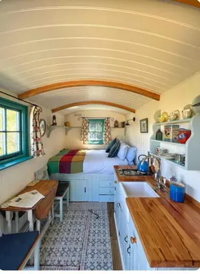 a room with a bed and a kitchen with a sink at Elderflower Hut in Port Isaac