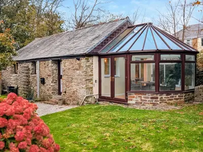 a house with a conservatory in a yard at Byre Cottage in Fowey