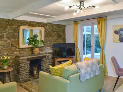 a living room with a couch and a fireplace at Byre Cottage in Fowey