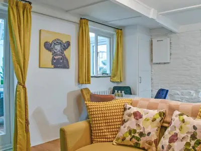 a living room with a couch and yellow curtains at Byre Cottage in Fowey