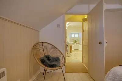 a wicker chair in a room with a bedroom at Grade II Listed Cottage Gorran Haven Sea Views in Gorran Haven