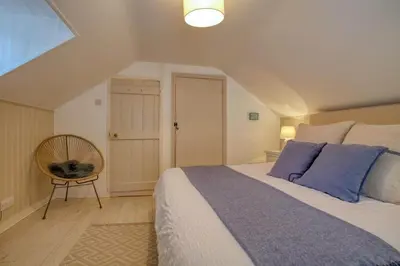 a bedroom with a large bed and a chair at Grade II Listed Cottage Gorran Haven Sea Views in Gorran Haven
