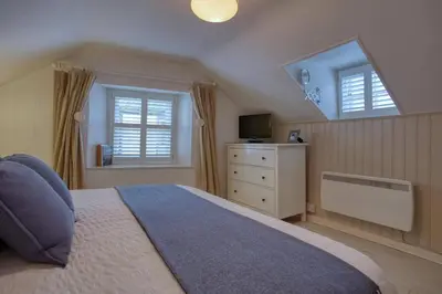 a bedroom with a large bed and a window at Grade II Listed Cottage Gorran Haven Sea Views in Gorran Haven