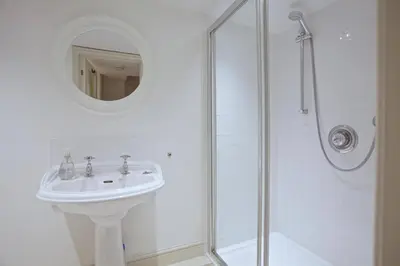 a white bathroom with a sink and a shower at Grade II Listed Cottage Gorran Haven Sea Views in Gorran Haven